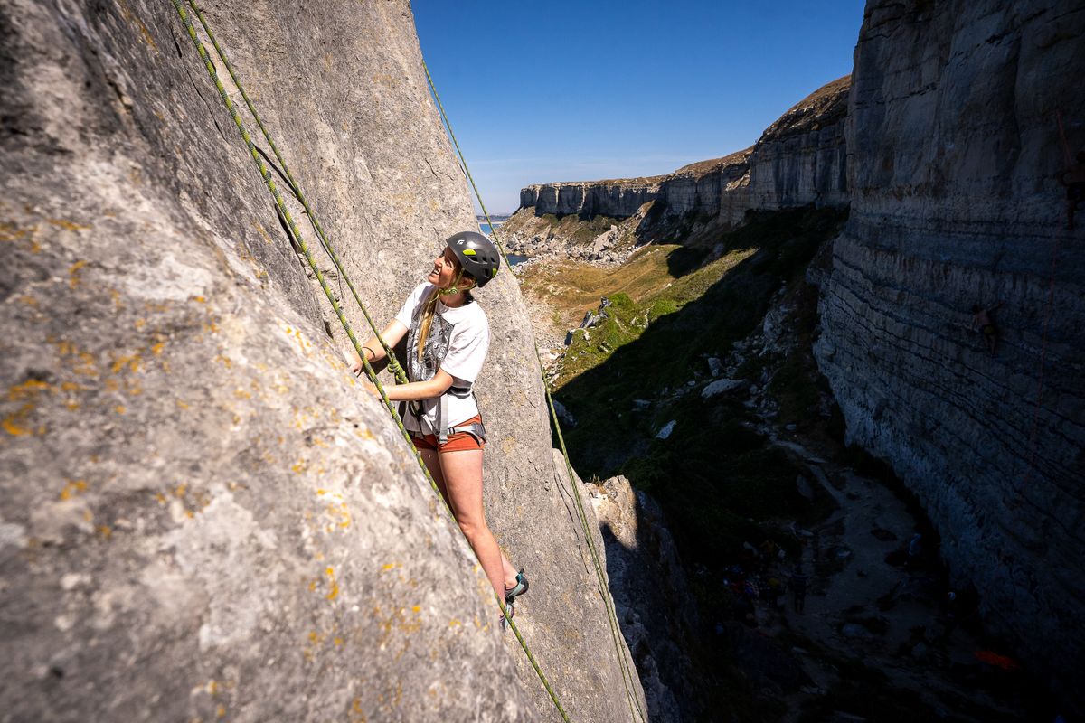 A young woman climbing up the side of a 10m wall